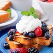 2 slices of pound cake, topped with berries and whipped cream on a plate.
