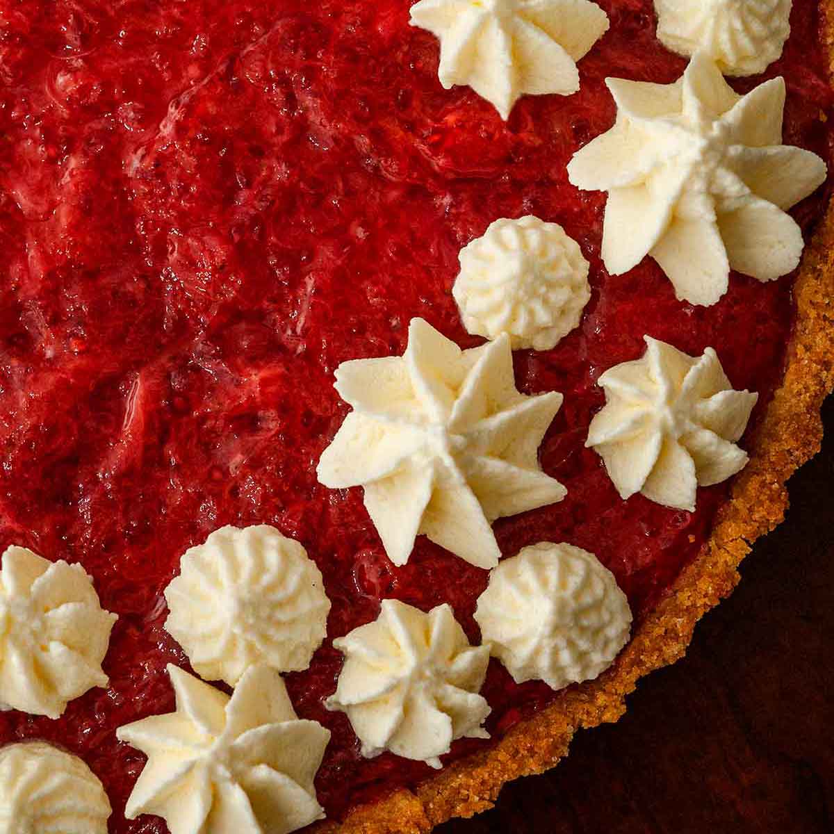 A strawberry rhubarb tart, topped with dots of whipped cream.