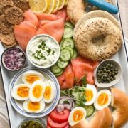 A tray of bagels with scattered, assorted bagel toppings.