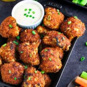 About a dozen cauliflower nuggets on a plate with a dipping sauce.