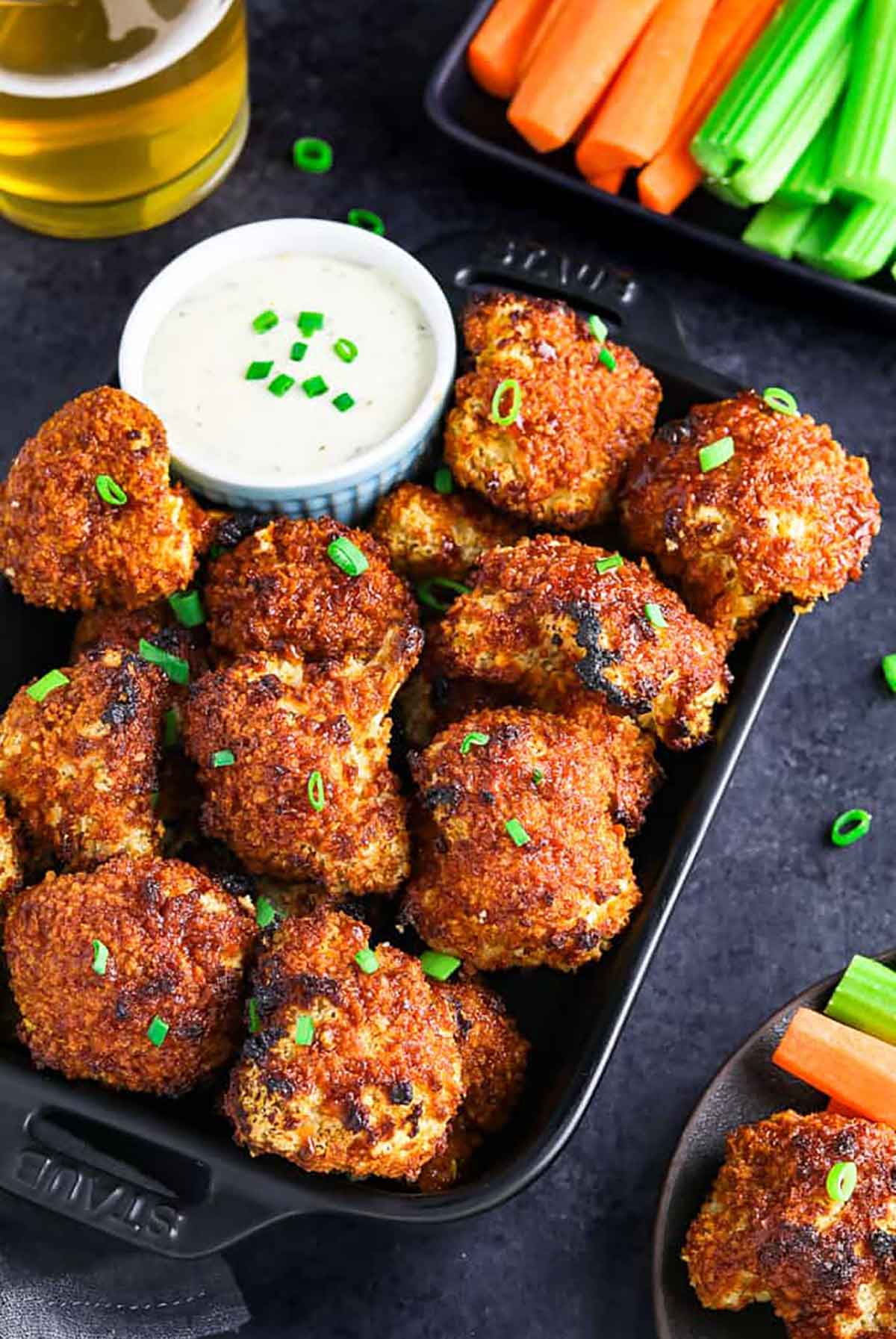 About a dozen cauliflower nuggets on a plate with a dipping sauce.