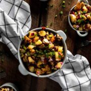 Fried potato salad in a bowl in the center of a table, on top of a kitchen towel.