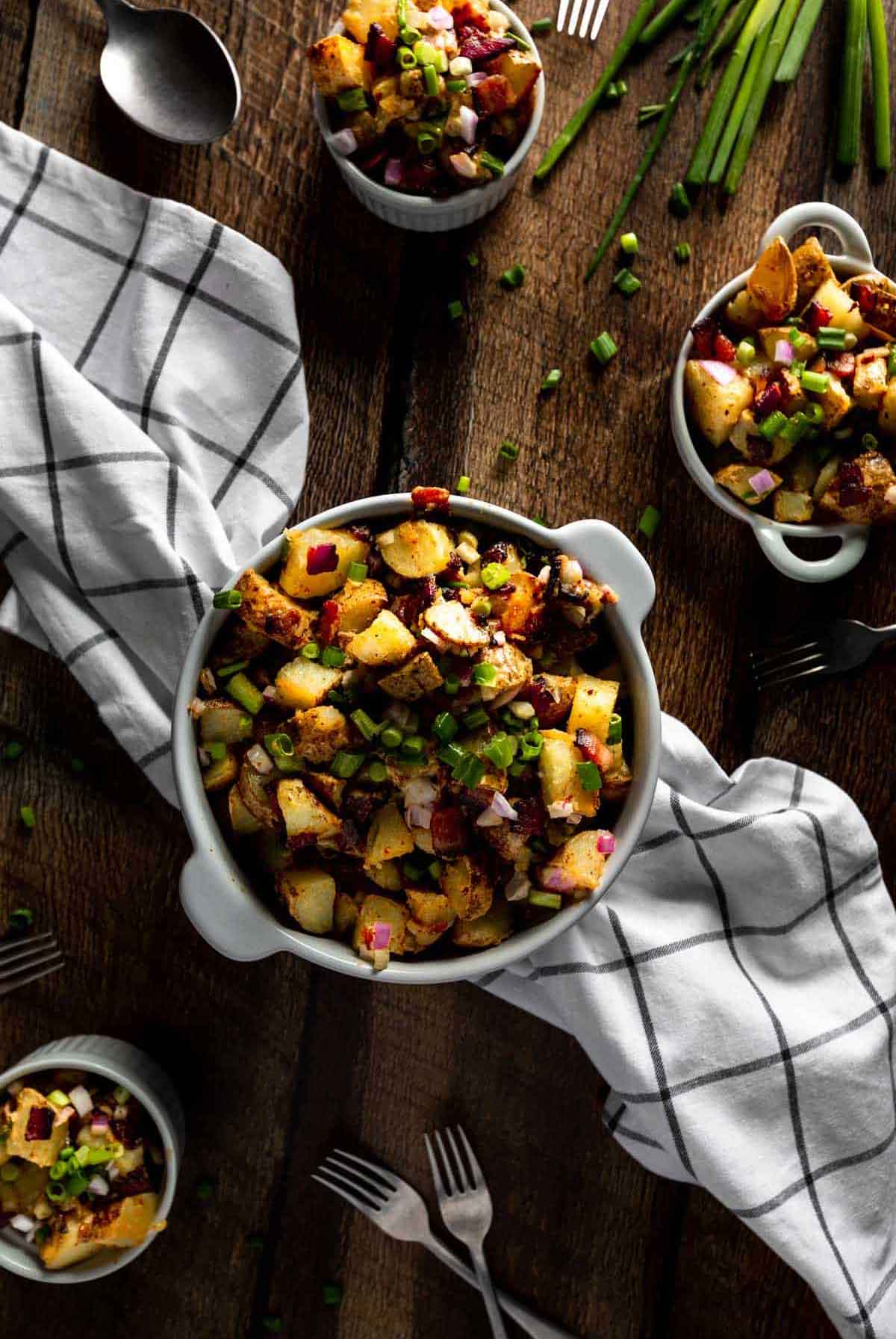 Fried potato salad in a bowl in the center of a table, on top of a kitchen towel.