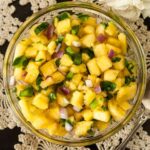 Pineapple jalapeño salsa in a small bowl on a lace tablecloth.