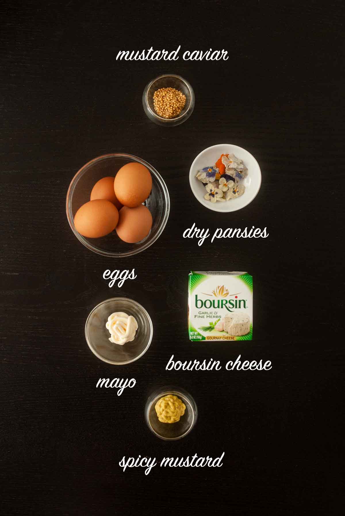 6 ingredients for making deviled eggs on a dark table with titles describing what they are.