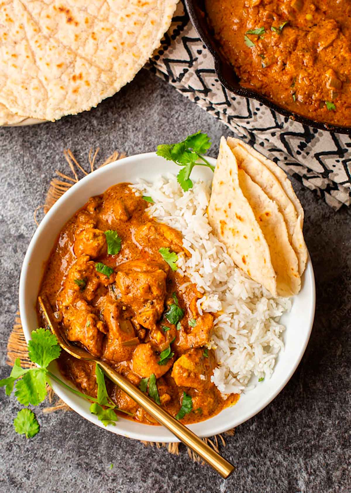 Pumpkin curry in a bowl with rice and bread on a table.