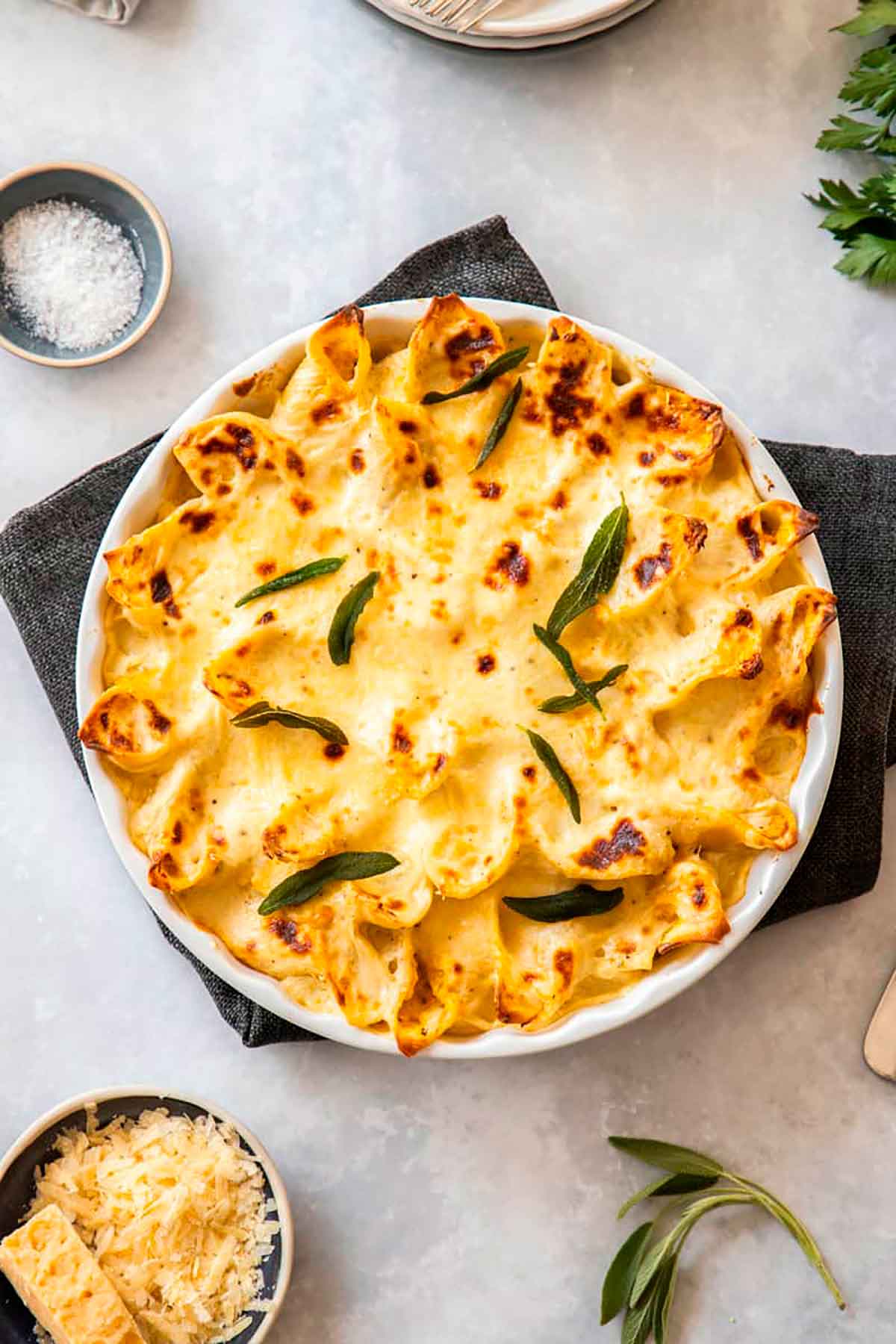 A round dish of baked pasta on a table, garnished with leaves.