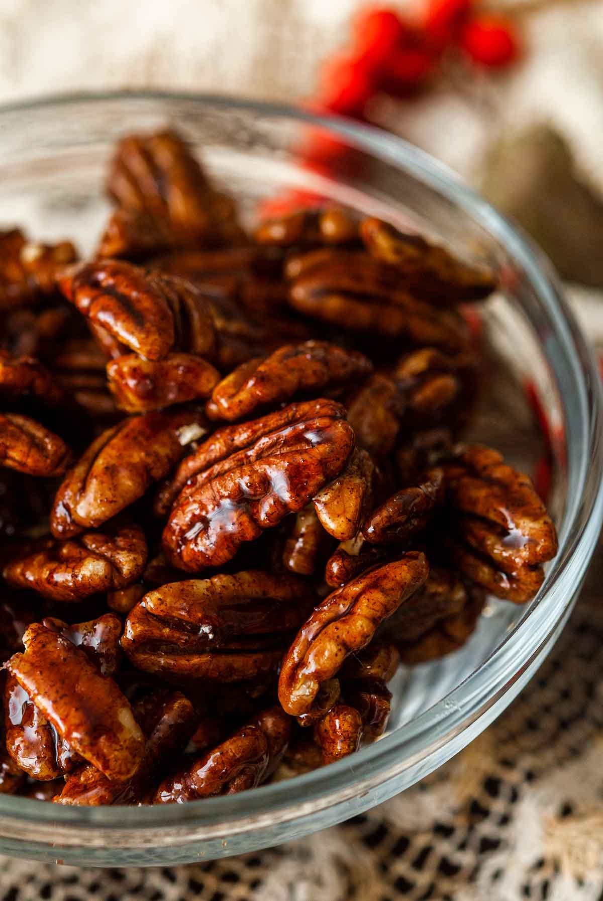 Candied pecans in a small bowl on a lace table cloth.