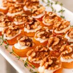 About 20 apricot appetizers on a plate, garnished with thyme.