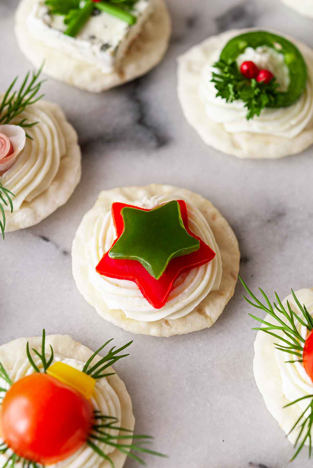 An appetizer with bell pepper stars on marble beside 5 other festive appetizers.