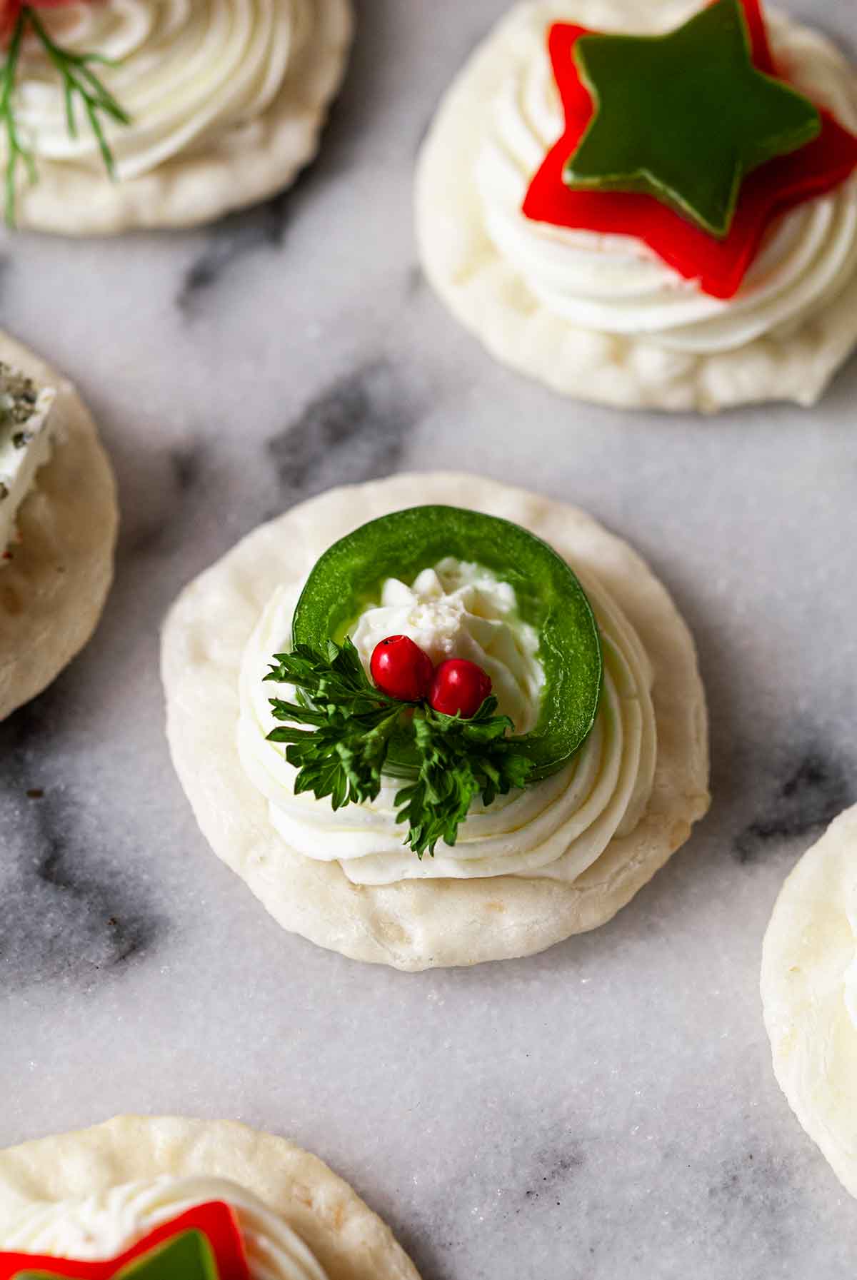 A jalapeno Christmas wreath appetizer on marble with 5 others.
