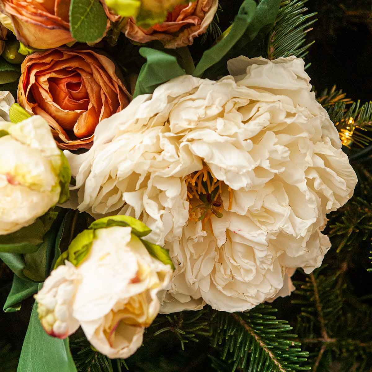 A hand positioning a bouquet of flowers in a Christmas tree.