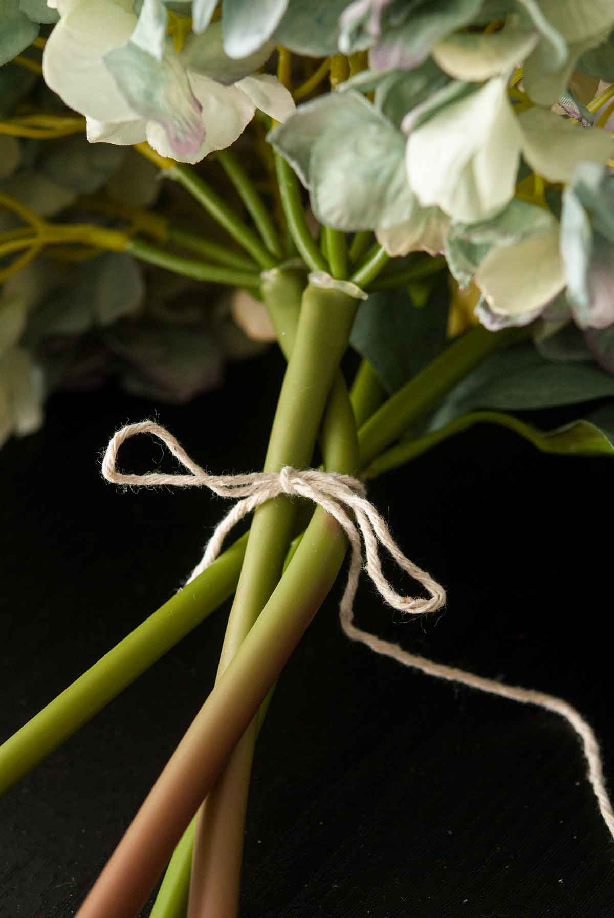 The stems of artificial hydrangeas tied with string.