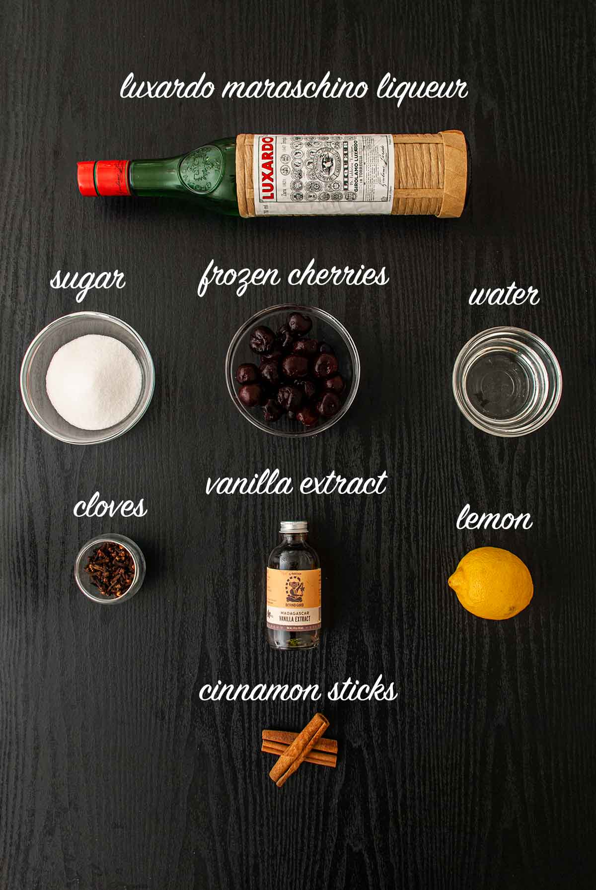 8 ingredients on a table for making maraschino cherries with labels saying what they are.