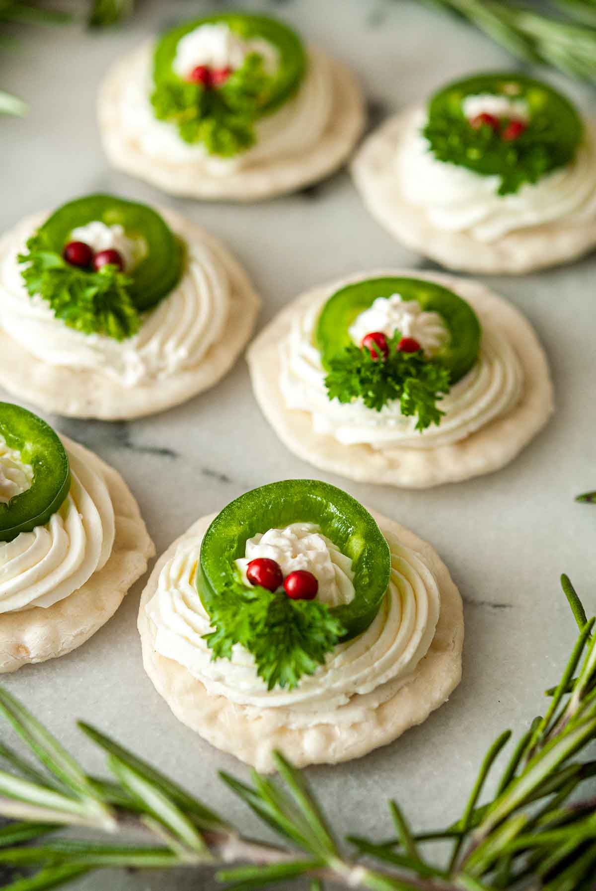 6 jalapeño wreath appetizers on marble with rosemary.