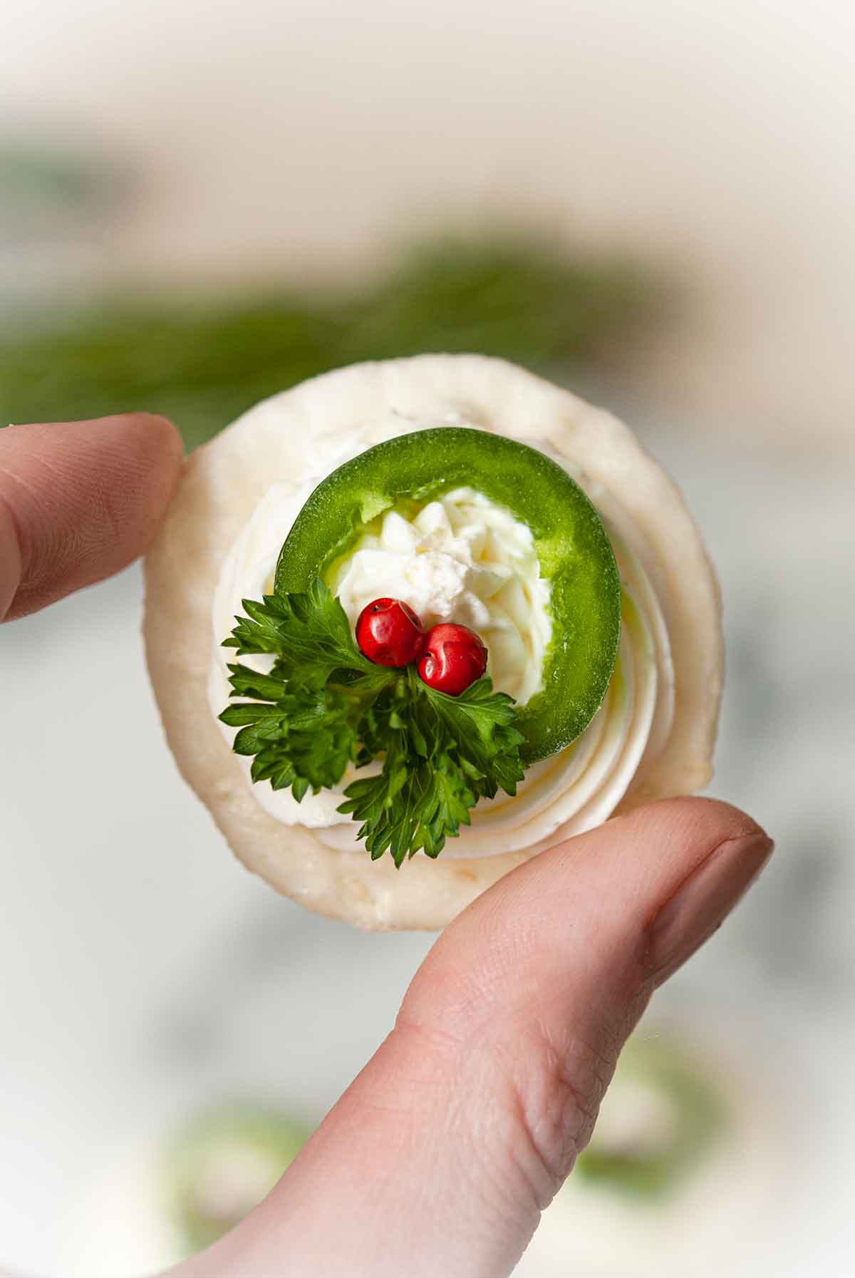 fingers holding a wreath appetizer.