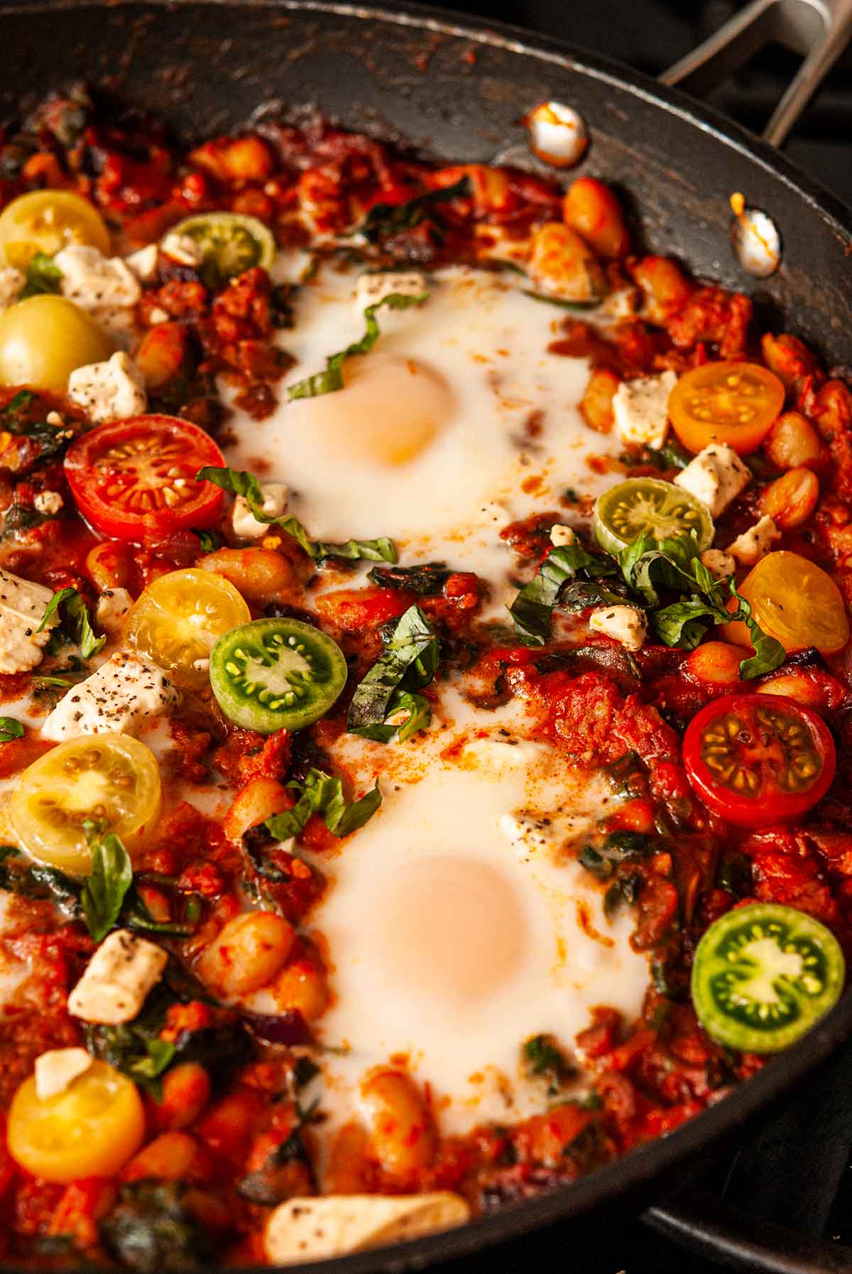 Italian Eggs in Purgatory in a pan with sliced cherry tomatoes.