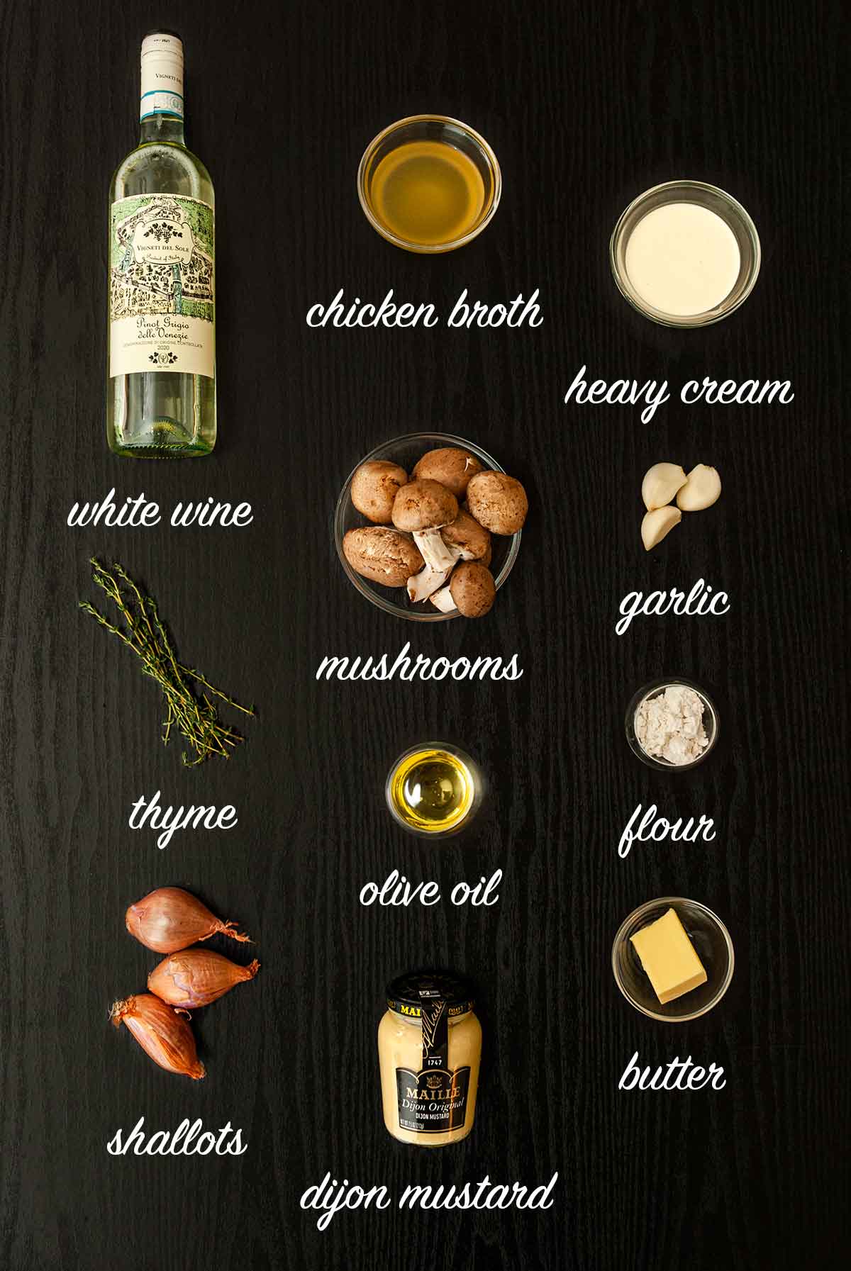 Ingredients on a table that make white wine mushroom sauce with text labels describing what they are..