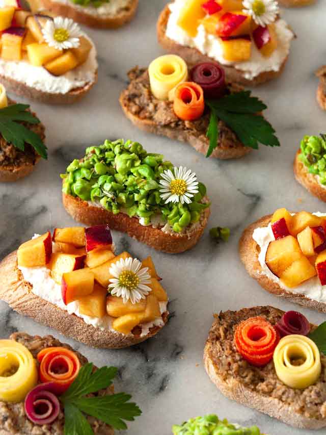 13 beautifully garnished crostini on a marble plate.