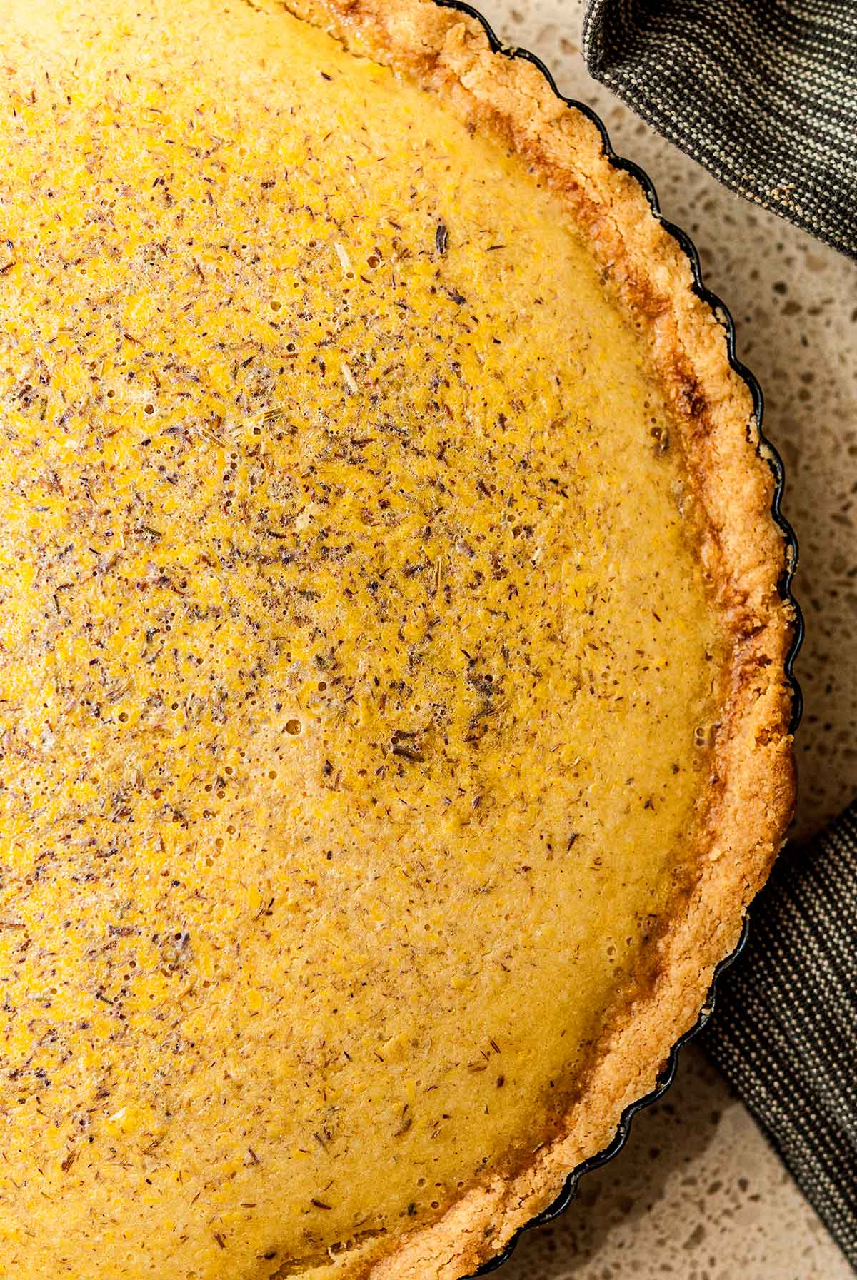 A cooked lavender lemon Easter tart beside a tea towel.