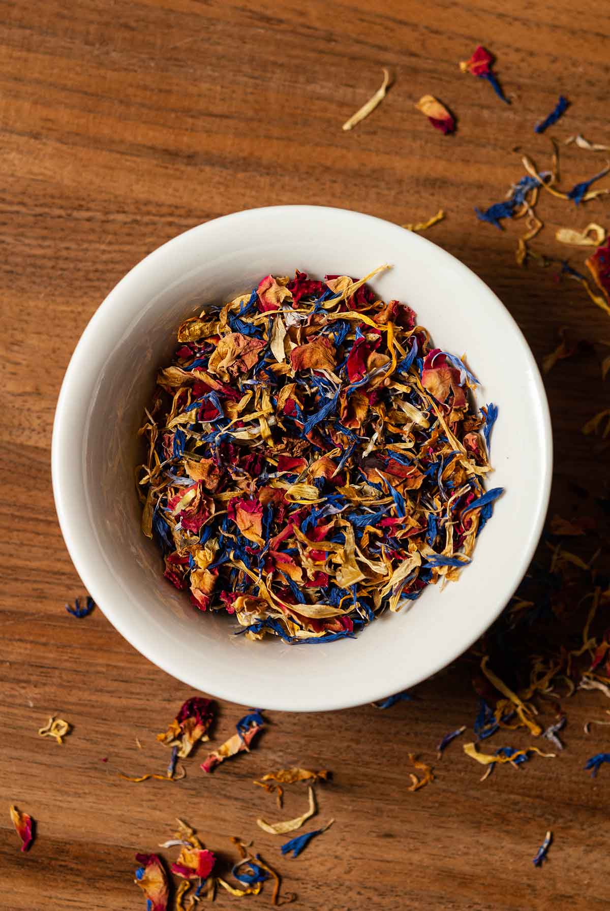 A bowl of dry flowers on a wooden table.