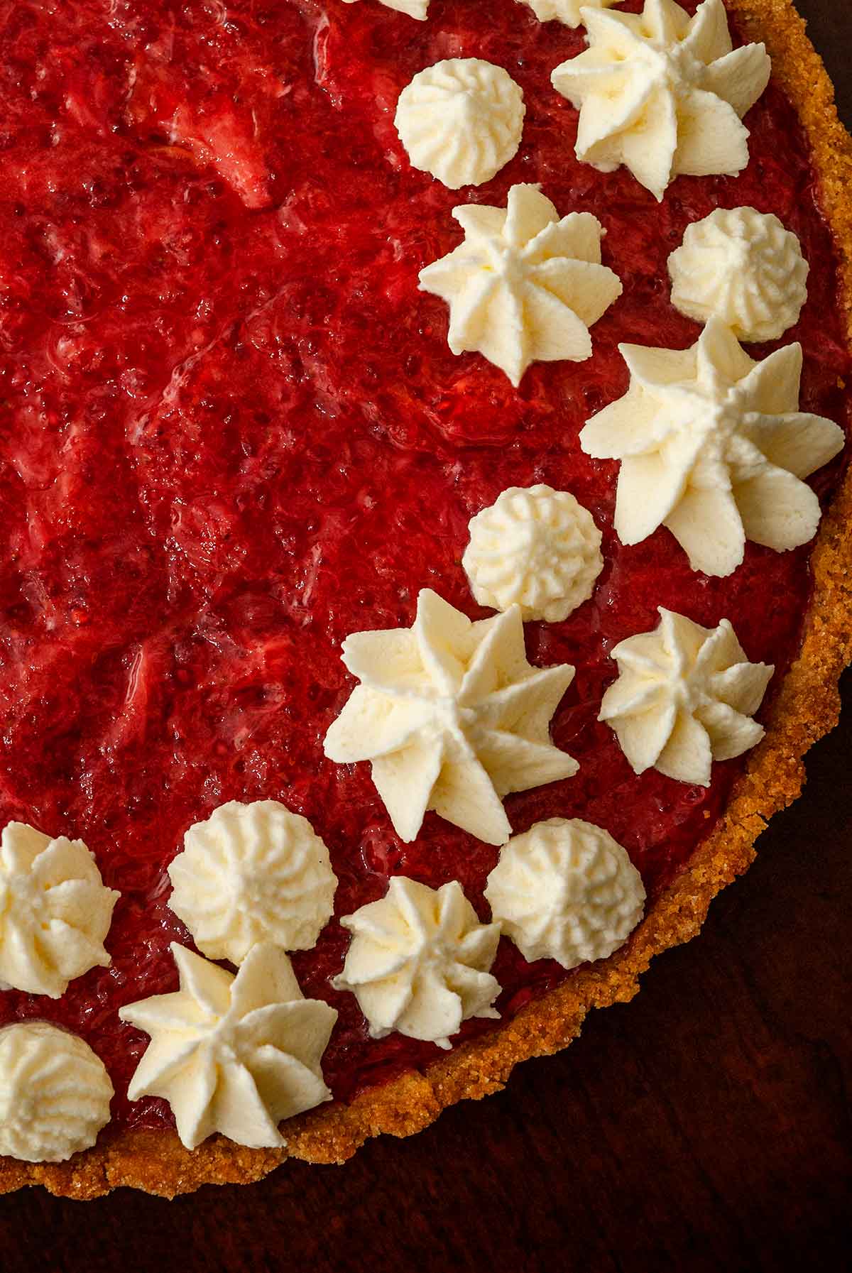 Whipped cream dots and stars on a strawberry rhubarb tart.
