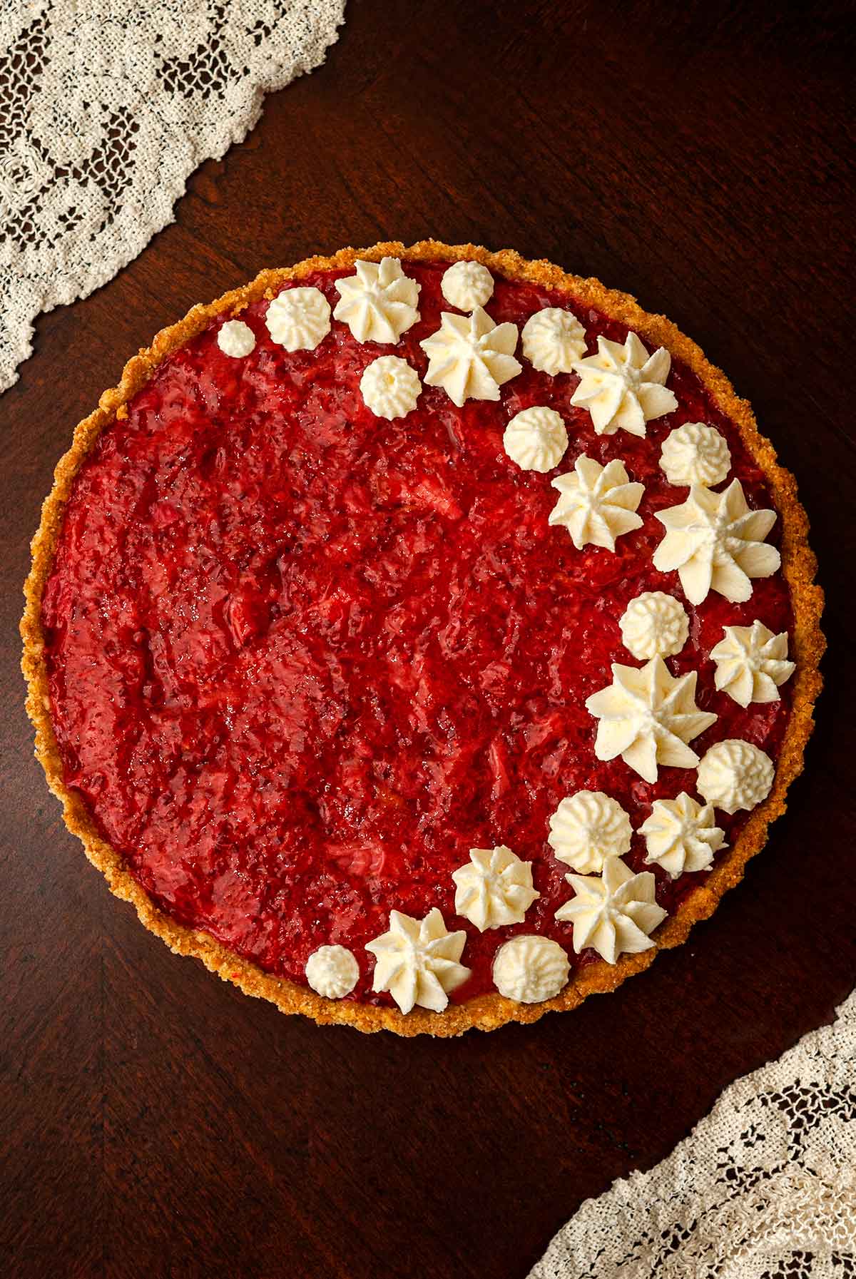 A strawberry rhubarb tart, topped with dots of whipped cream.