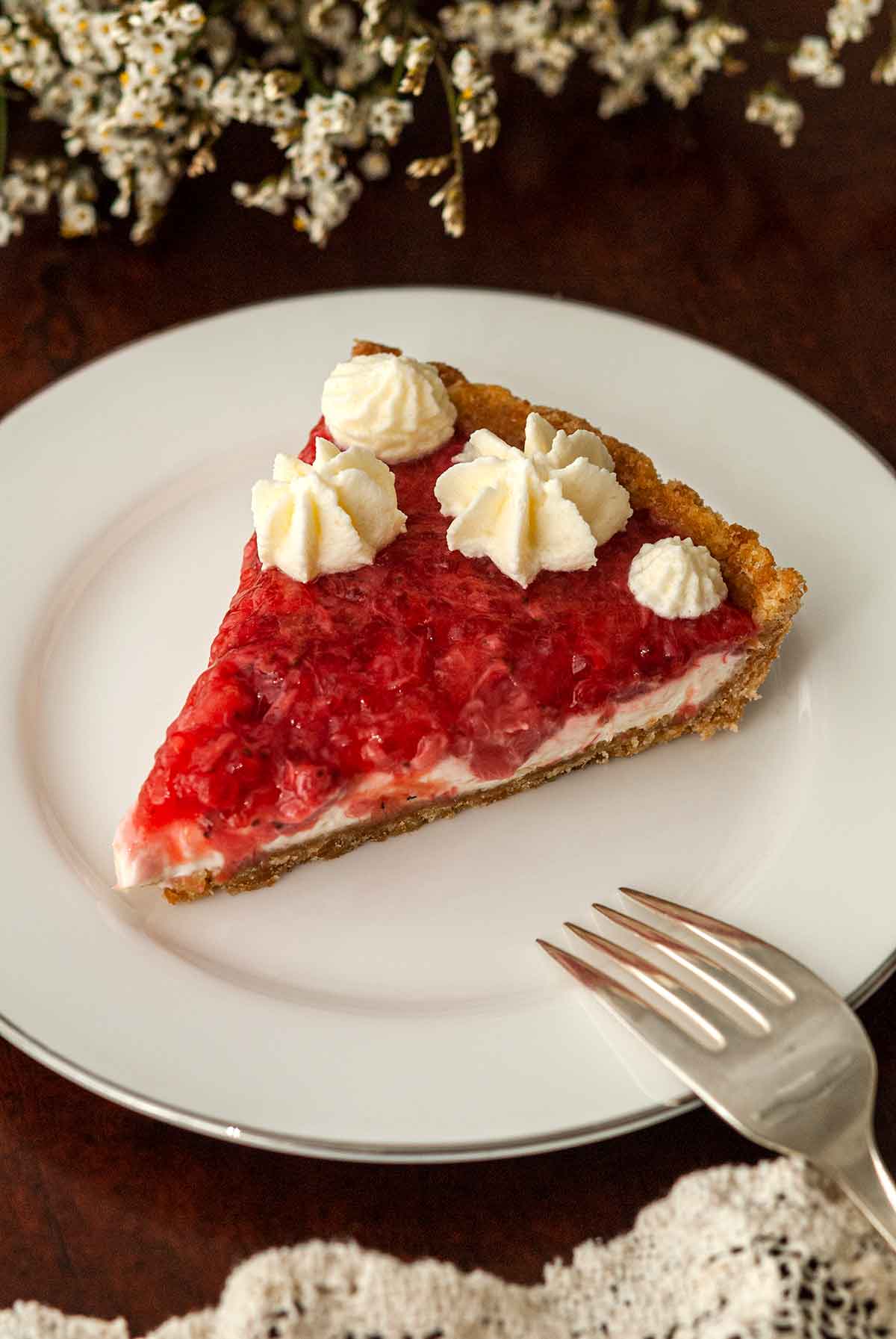A slice of strawberry rhubarb tart on a plate with a fork.