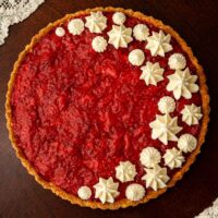 A strawberry rhubarb tart, topped with dots of whipped cream.