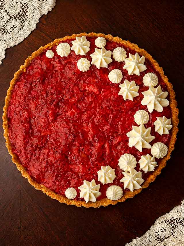 A strawberry rhubarb tart, topped with dots of whipped cream.