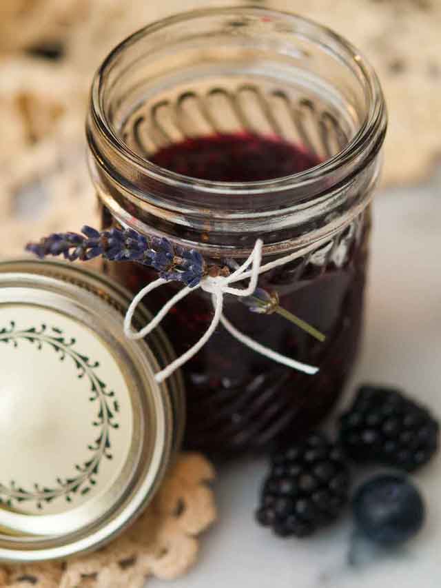 a jar of black and blueberry jam with a sprig of lavender tied to the glass.