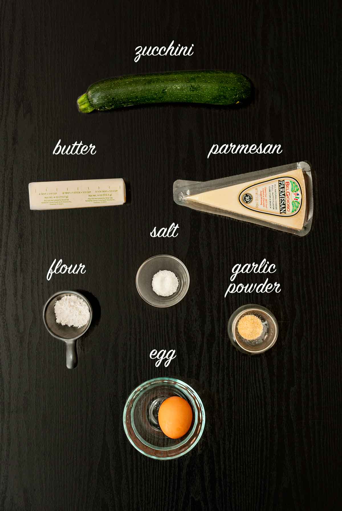 7 labeled ingredients for making zucchini crust on a table.