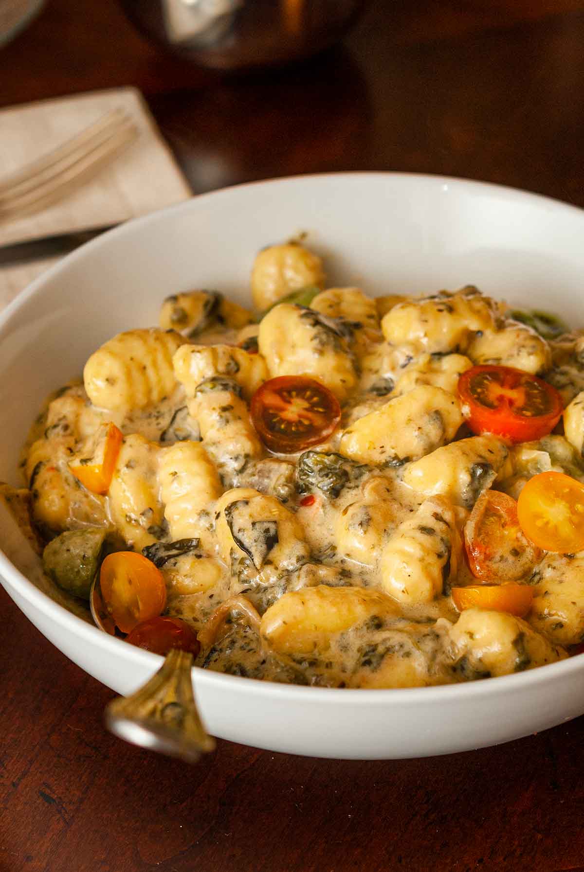 A bowl of Tuscan gnocchi in a bowl with a spoon on a table.