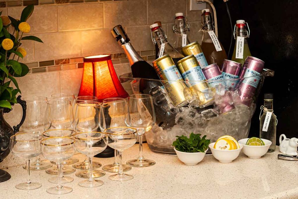 A bar set-up of drinks in a cooler, surrounding by garnishes and glasses.