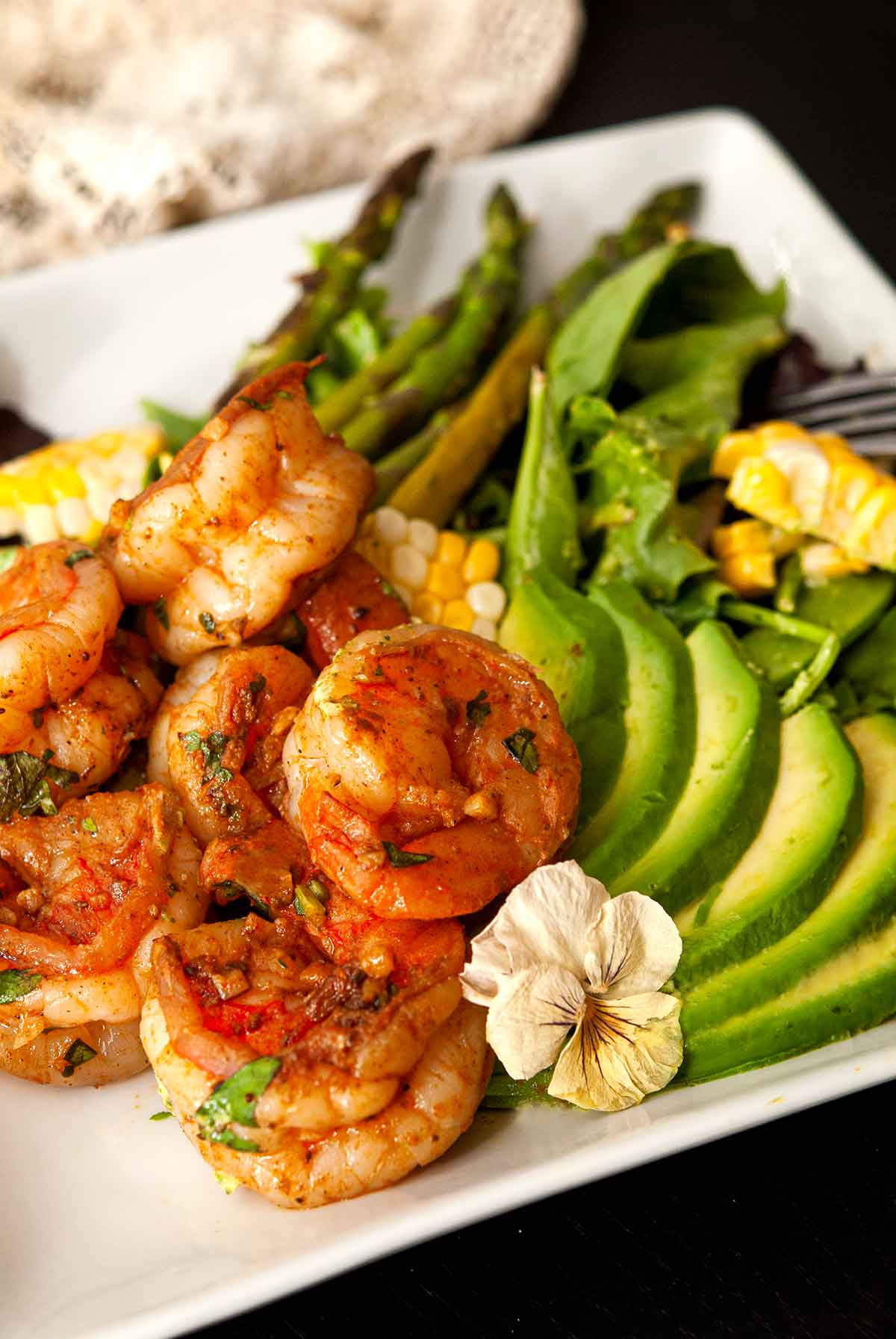 A plate of cilantro lime shrimp and vegetables, garnished with a flower.