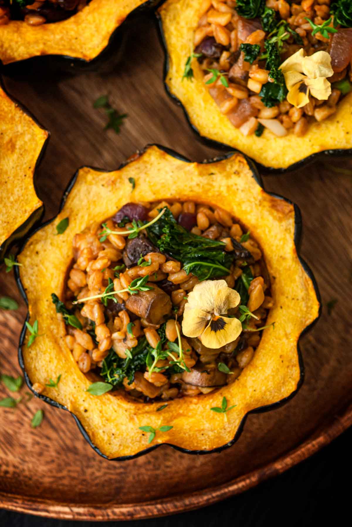 The stuffing in 1 of 4 acorn squash, garnished with thyme and a flower.