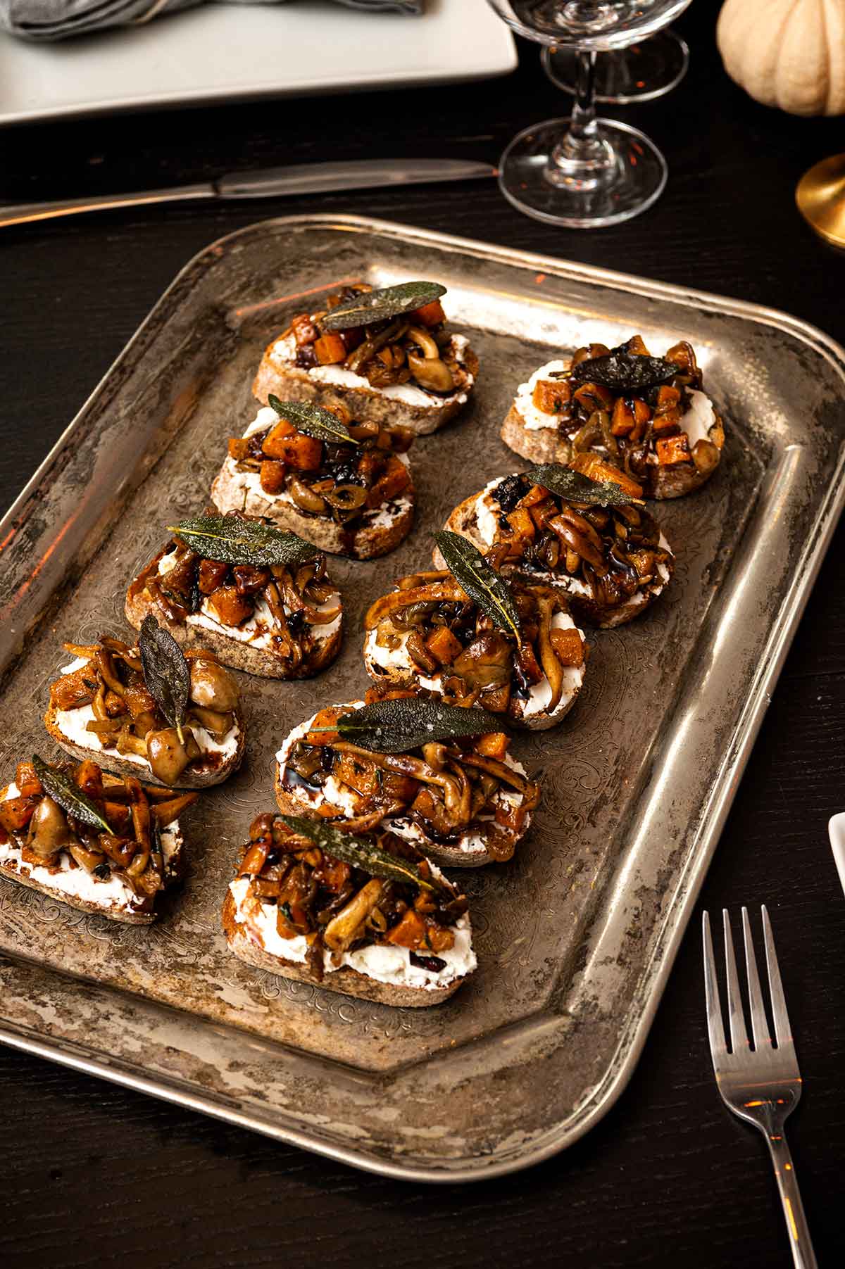 A silver tray with 10 crostini on a table.