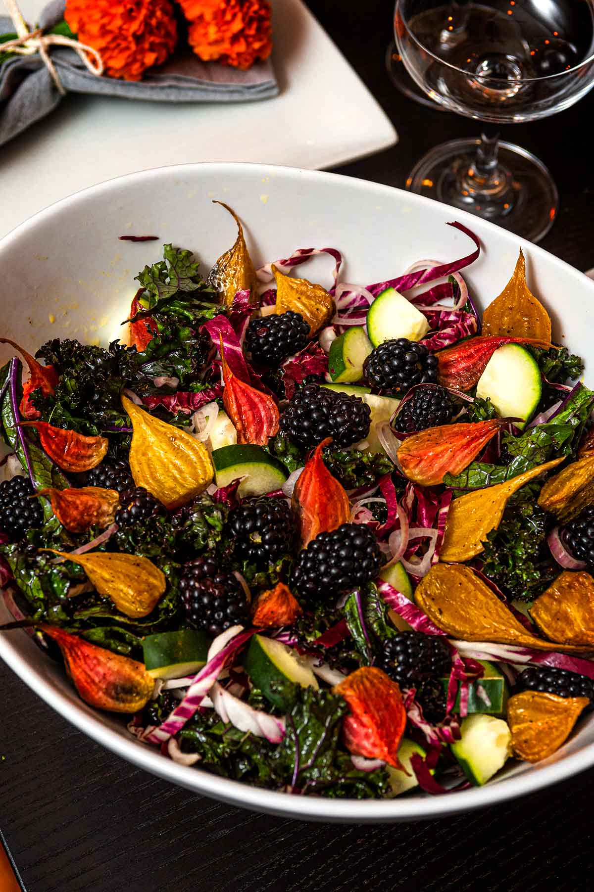A bowl of beet salad with blackberries on a table.