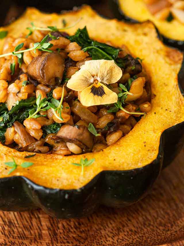 A stuffed acorn squash garnished with a flower and thyme.
