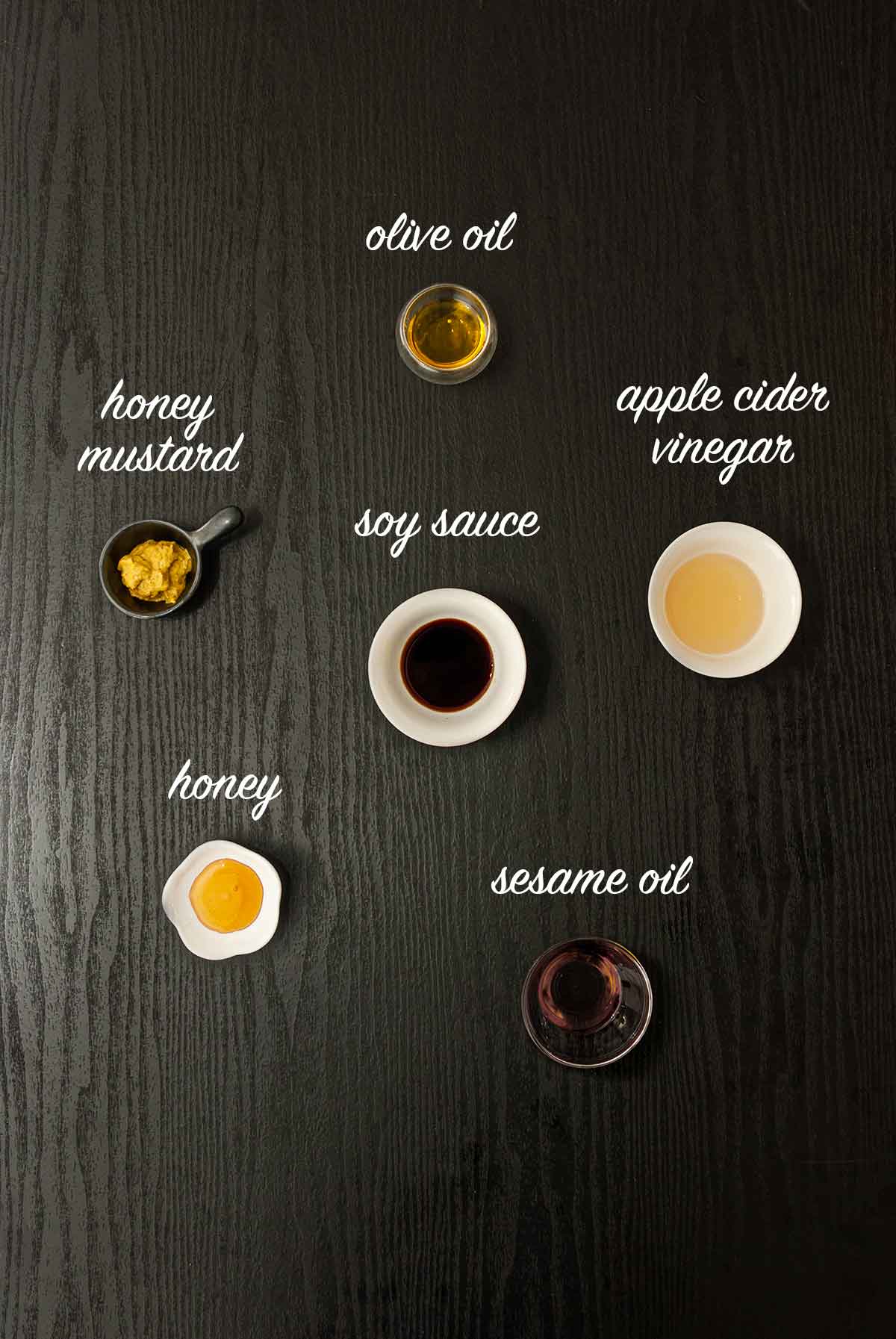 6 ingredients on a table that make apple cider vinaigrette. 