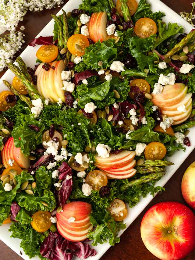 The top of an apple salad beside 2 apples on a table.