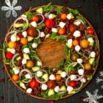 A flamboyantly garnished salad on a table in the shape of a wreath with a few scattered Christmas decorations.