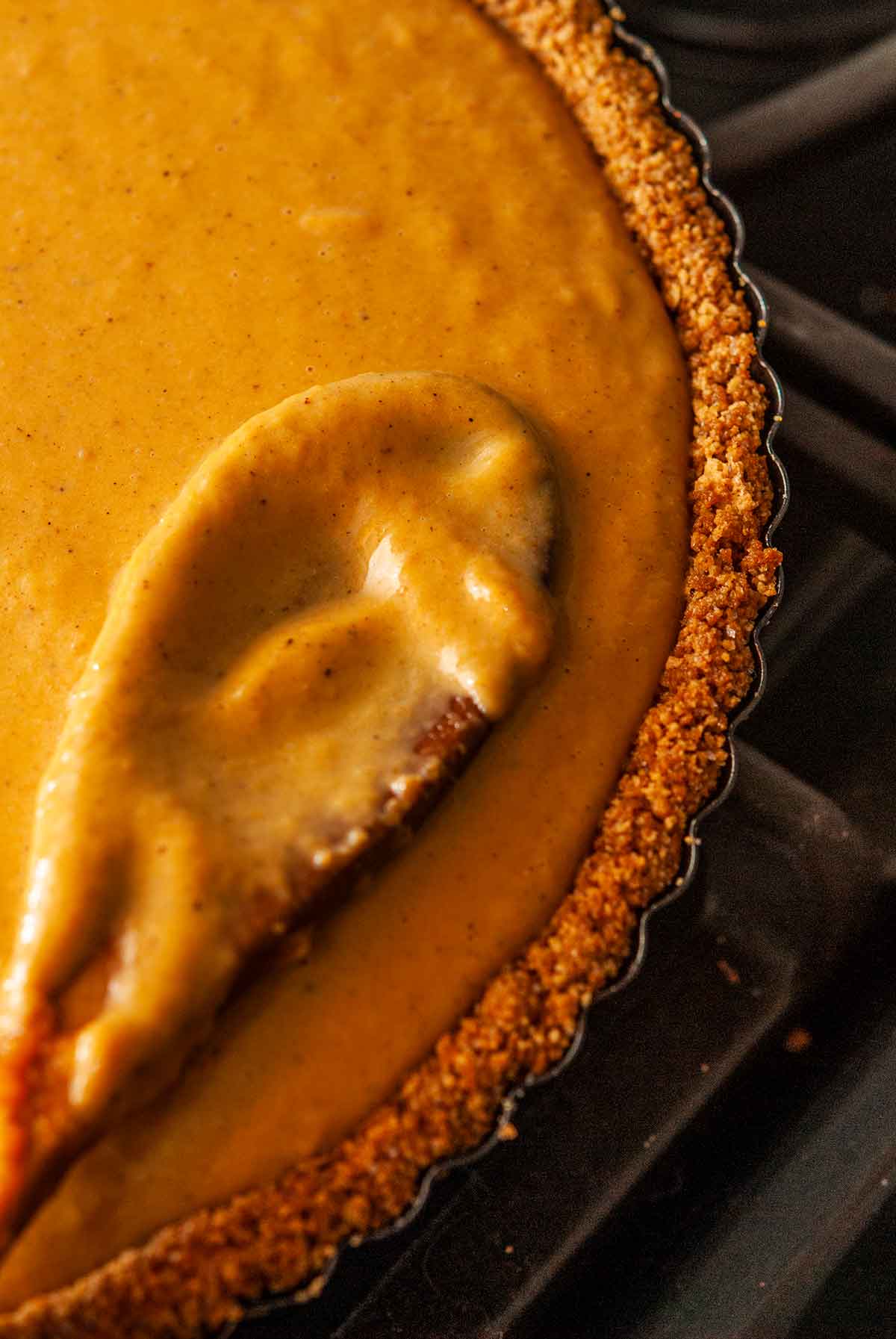 A mixing spoon pressing pie filling to the edges of a pie crust.