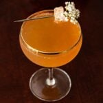 A garnished mulled ginger apple cider mimosa on a table.