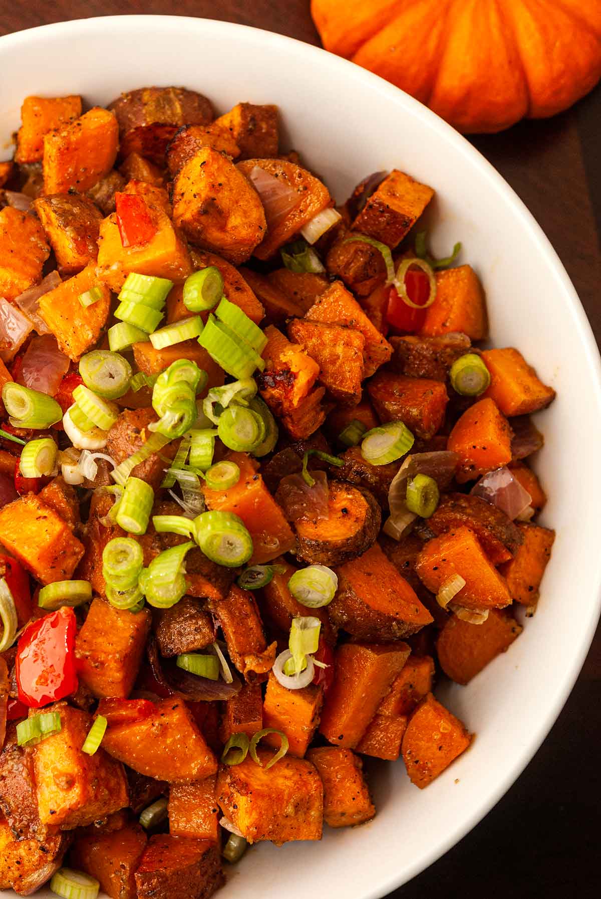 Sweet potato hash in a bowl, sprinkled with scallions.