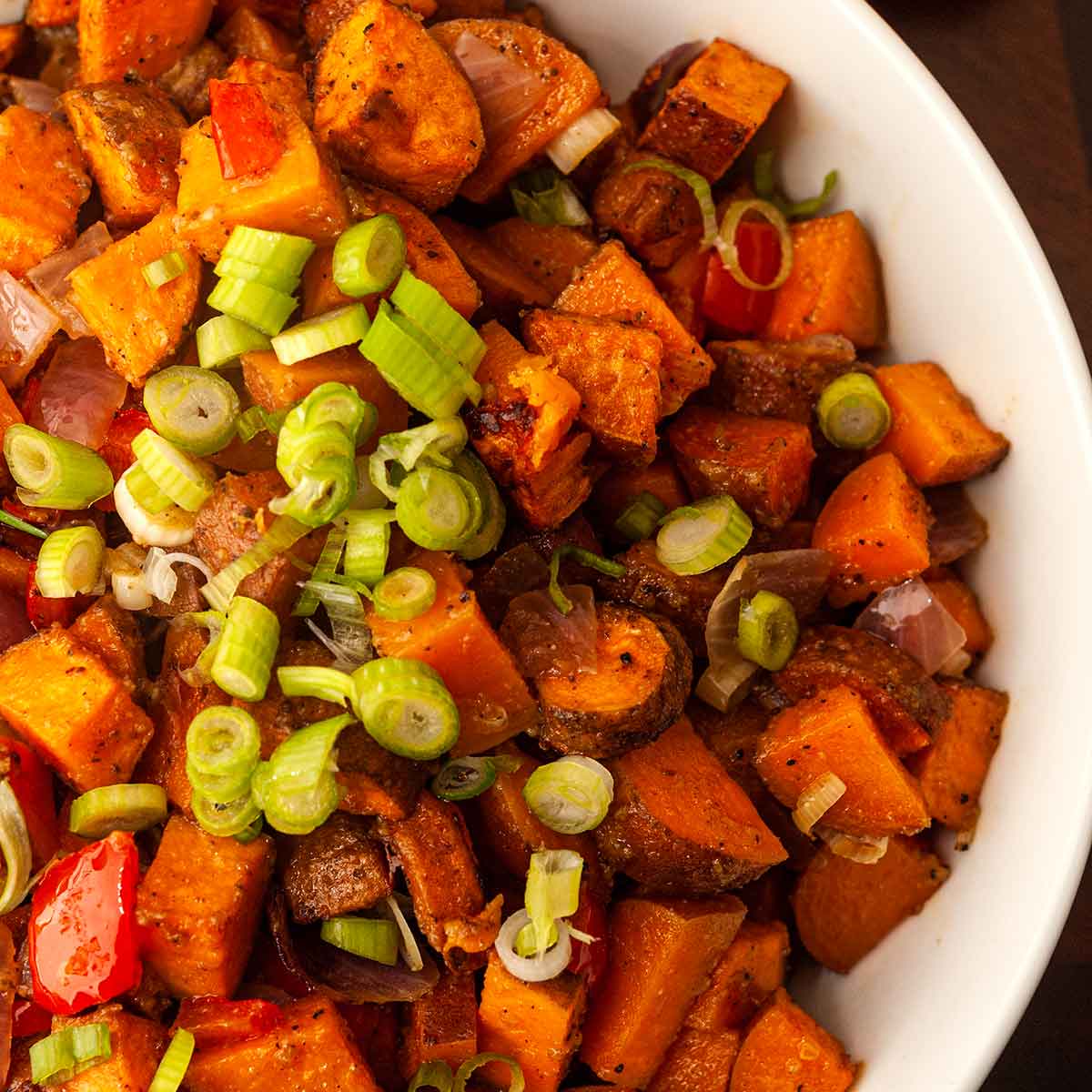 Sweet potato hash in a bowl, sprinkled with scallions.