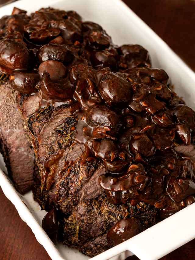 Top round roast beef in a tray with mushroom sauce.