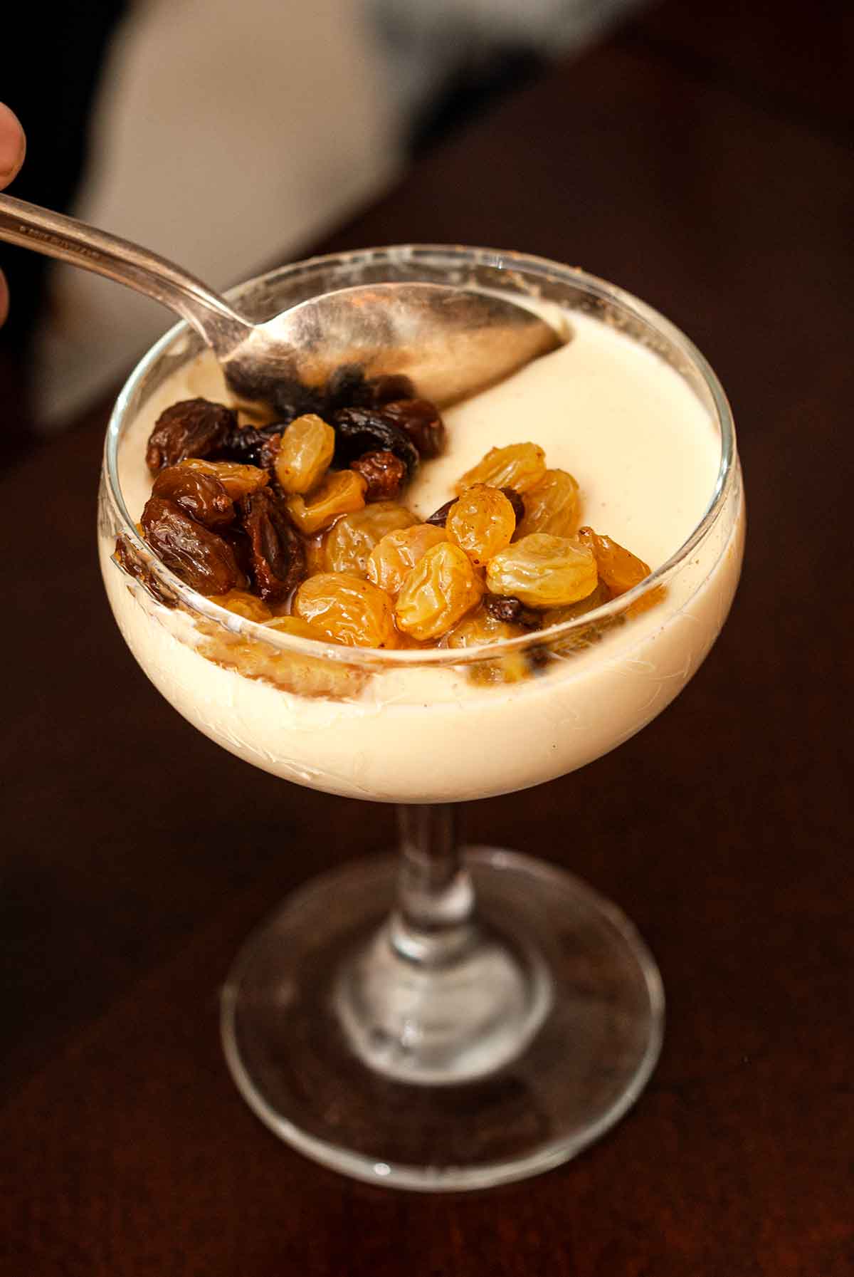 The rum-soaked raisins on a chai-spiced eggnog panna cotta with a spoon.