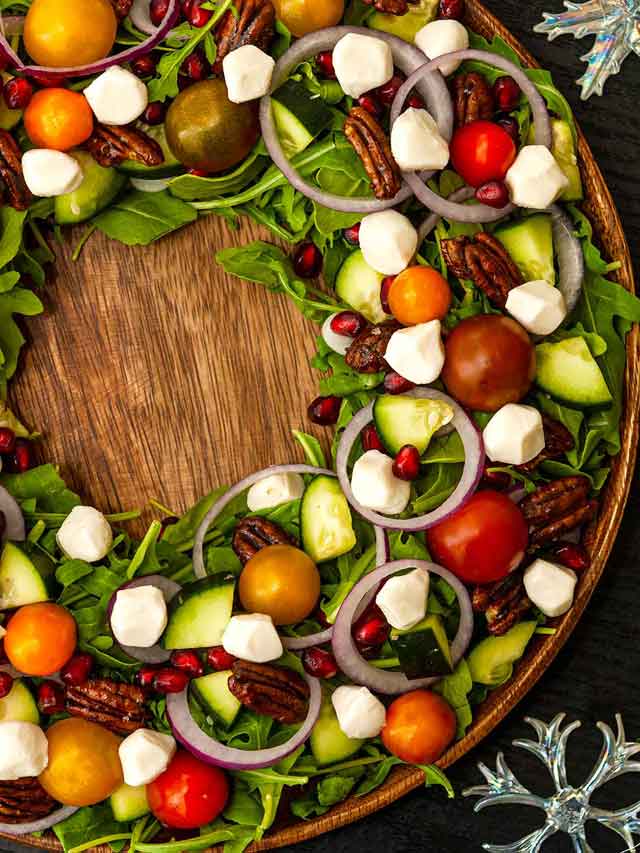 A salad that looks like a Christmas wreath on a table.