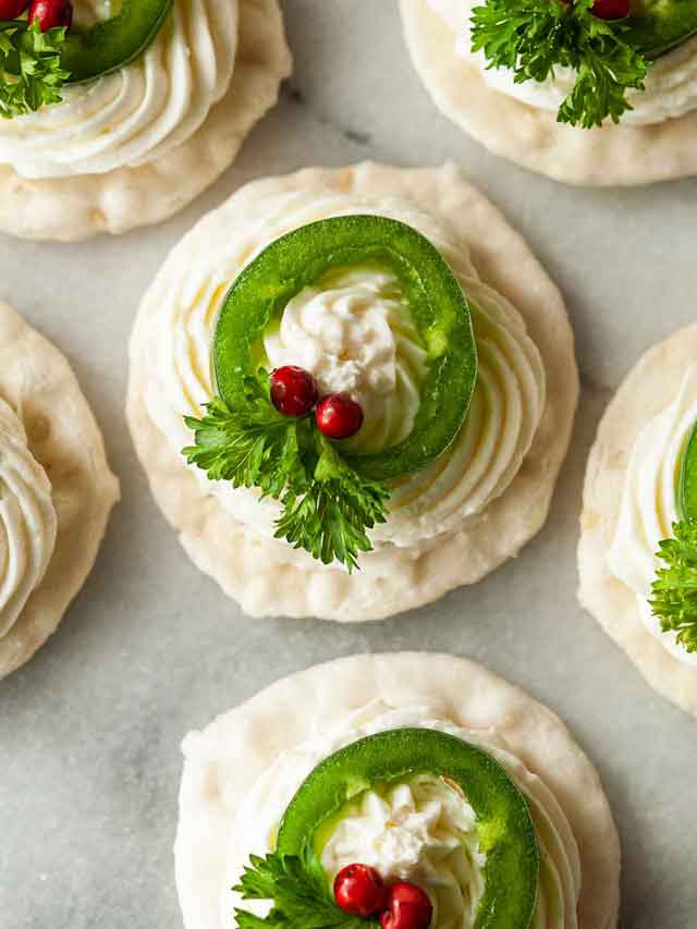 5 jalapeño wreath appetizers on marble with pink peppercorns, cheese and parsley.